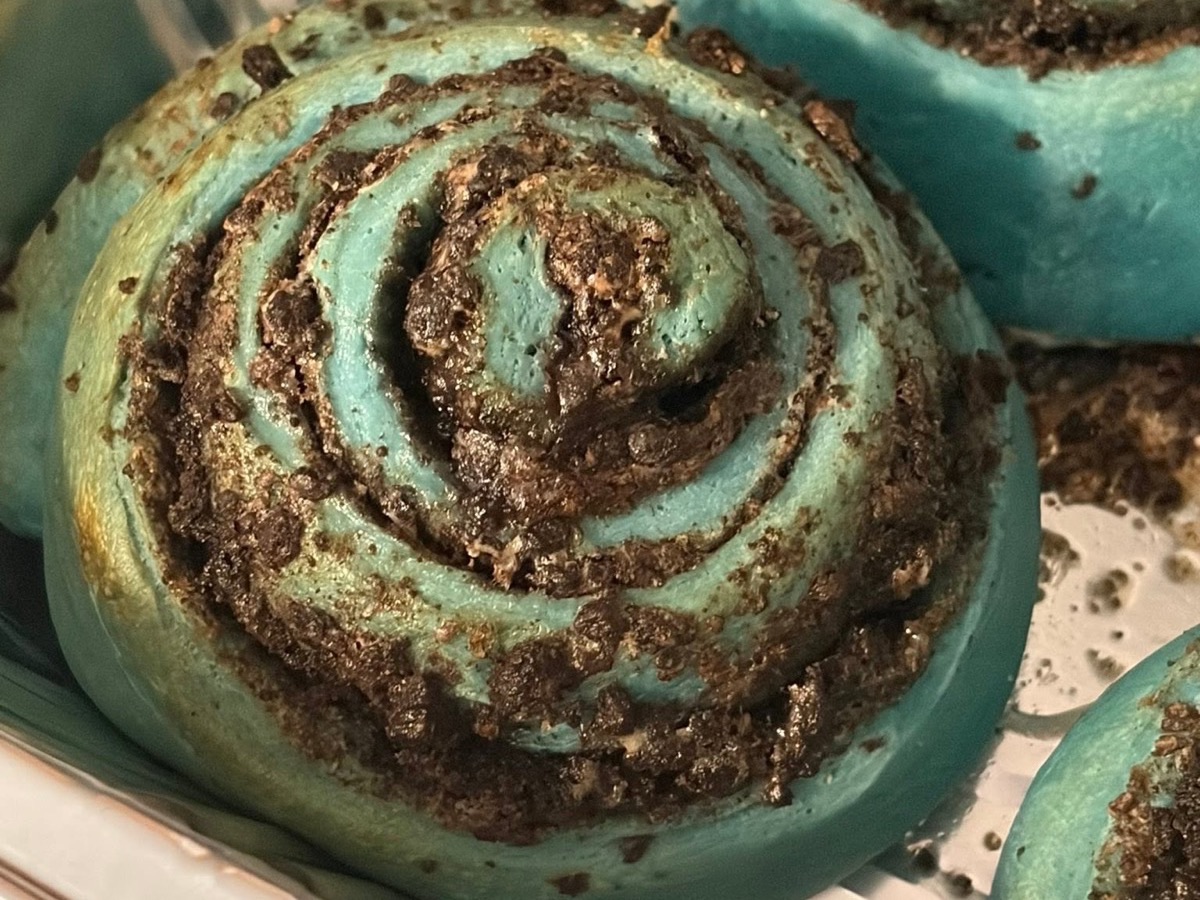 Close-up of a teal frosting swirl topped with cookie crumbs