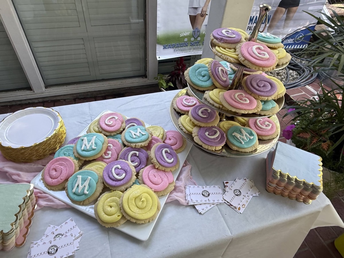 Tiered display of pastel monogram cookies at an outdoor party