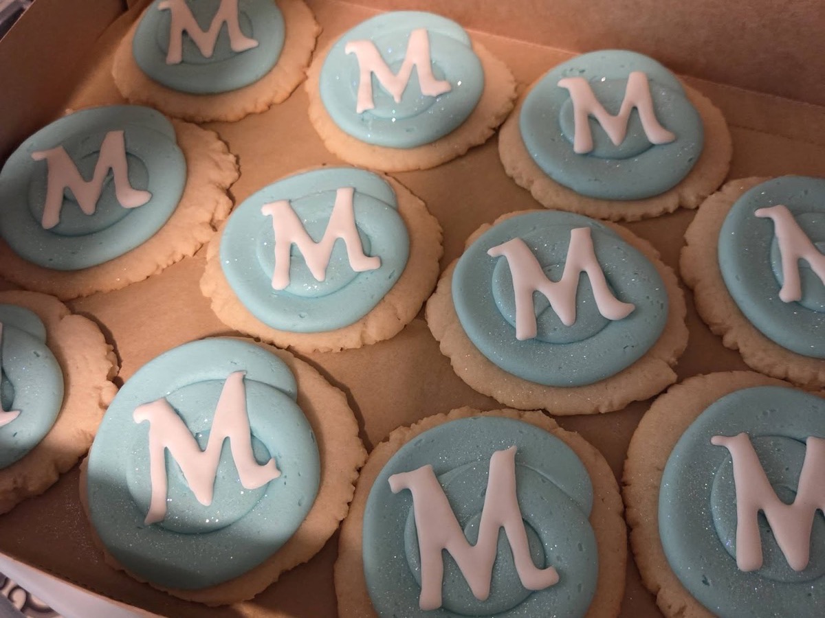 Teal frosted sugar cookies decorated with the letter M