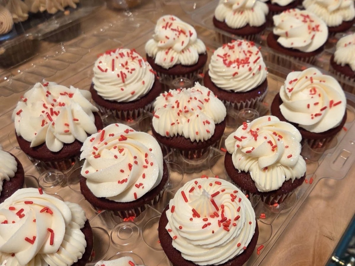 Red velvet cupcakes topped with white frosting and red sprinkles