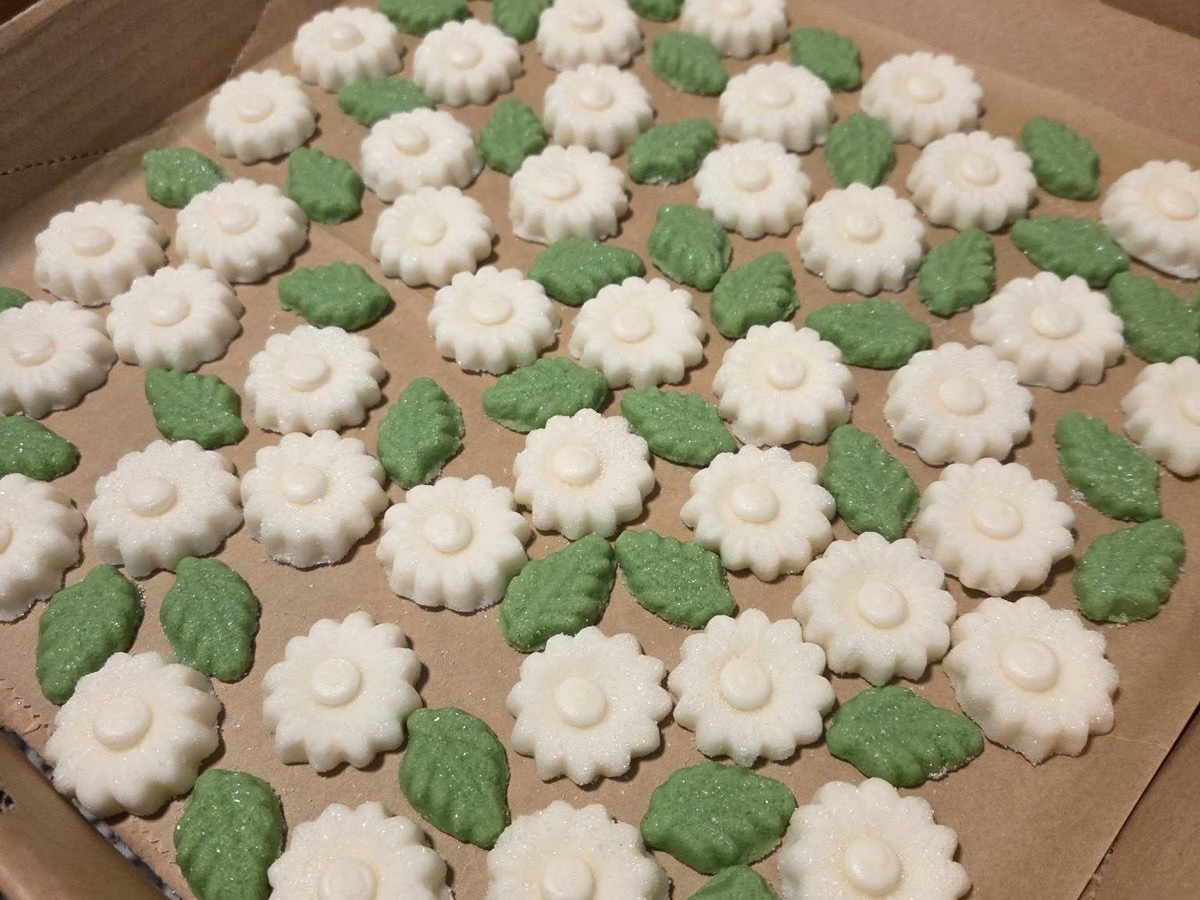 White flower and green leaf sugar cookies arranged in rows