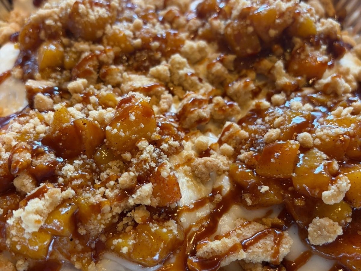 Peach cobbler topped with crumble and caramel sauce